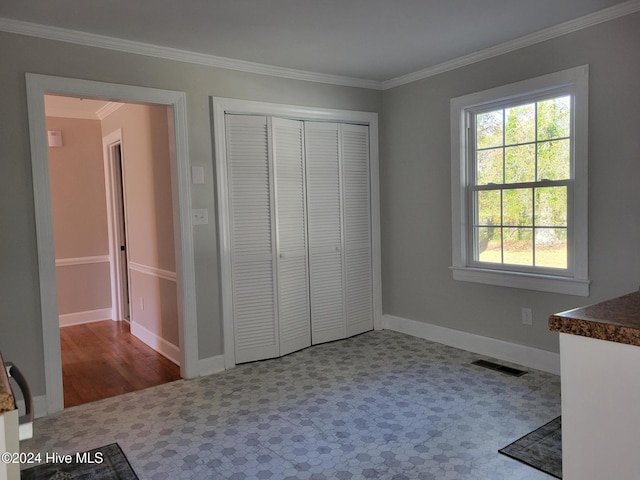 unfurnished bedroom with crown molding and a closet