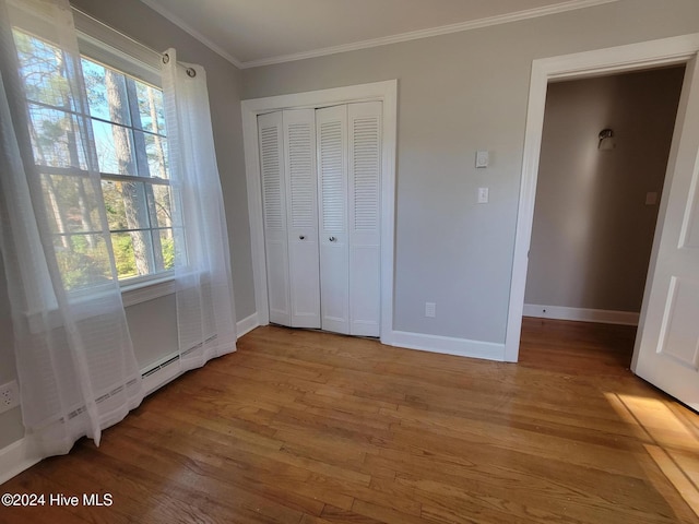 unfurnished bedroom featuring multiple windows, crown molding, and wood-type flooring