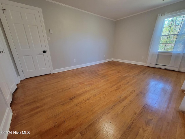 spare room with light hardwood / wood-style floors, ornamental molding, and baseboard heating