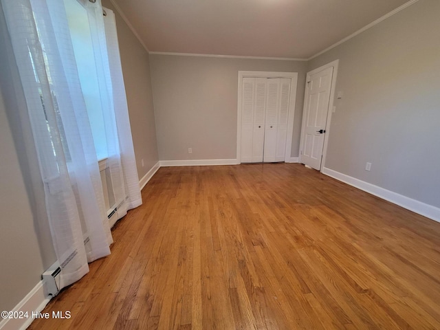 unfurnished room featuring crown molding, light hardwood / wood-style flooring, and a baseboard heating unit