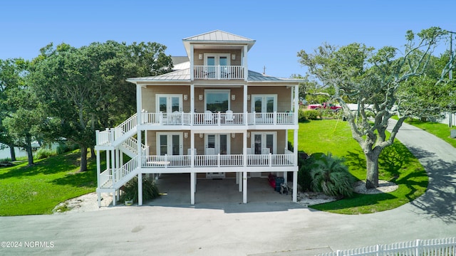 beach home featuring a carport, a balcony, covered porch, and a front yard