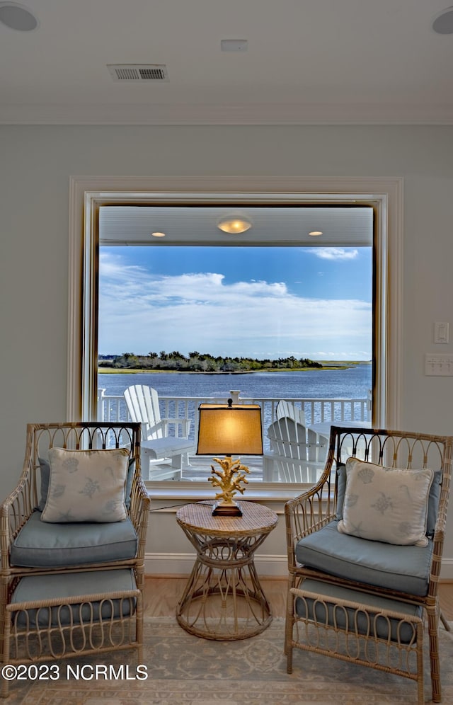 sitting room with ornamental molding, a water view, and wood-type flooring