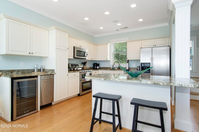 kitchen featuring a kitchen island, appliances with stainless steel finishes, wine cooler, and light hardwood / wood-style floors