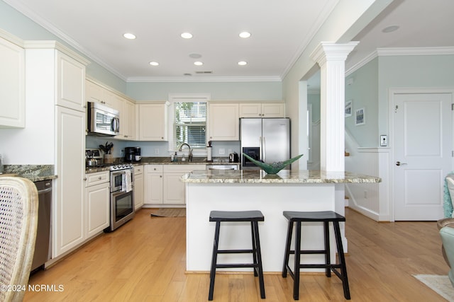 kitchen featuring appliances with stainless steel finishes, a center island, dark stone countertops, and sink