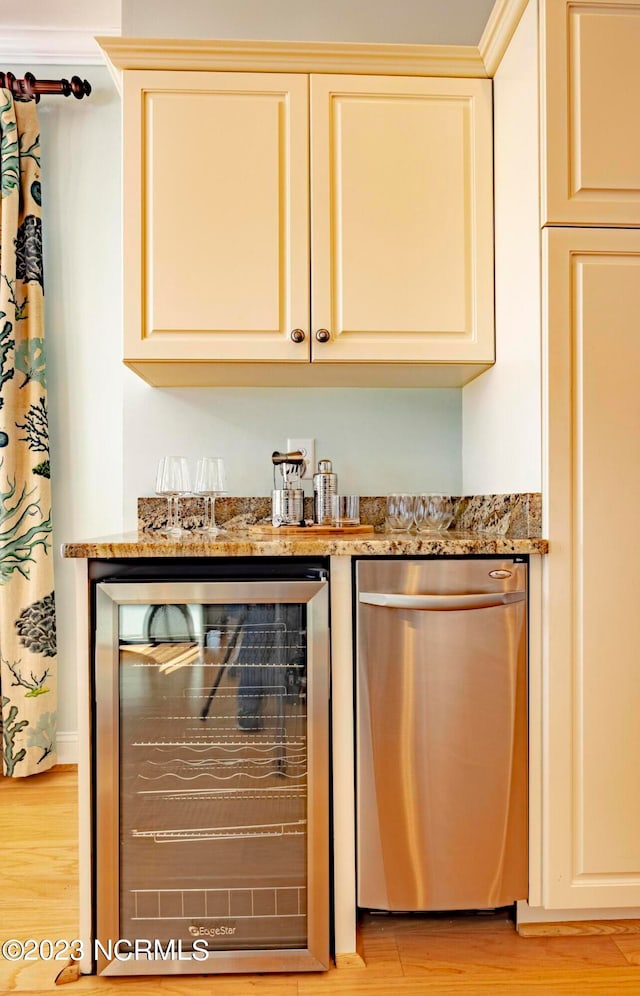 bar with stone counters, cream cabinetry, light wood-type flooring, dishwasher, and wine cooler