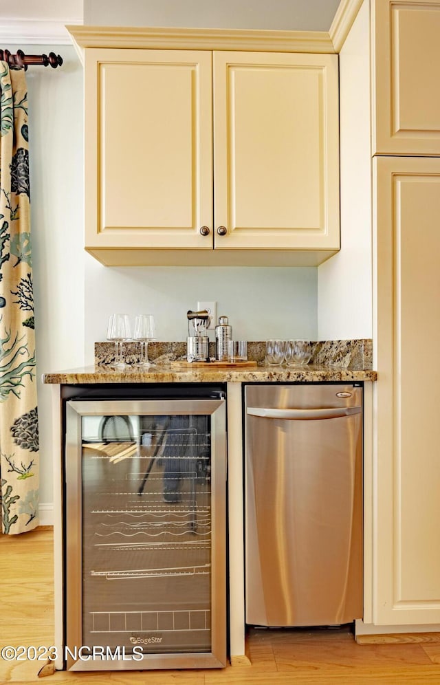 bar with stainless steel dishwasher, beverage cooler, cream cabinetry, and dark stone counters