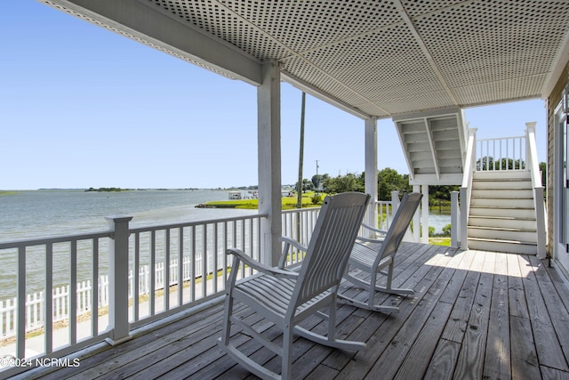 wooden deck featuring a water view and a beach view