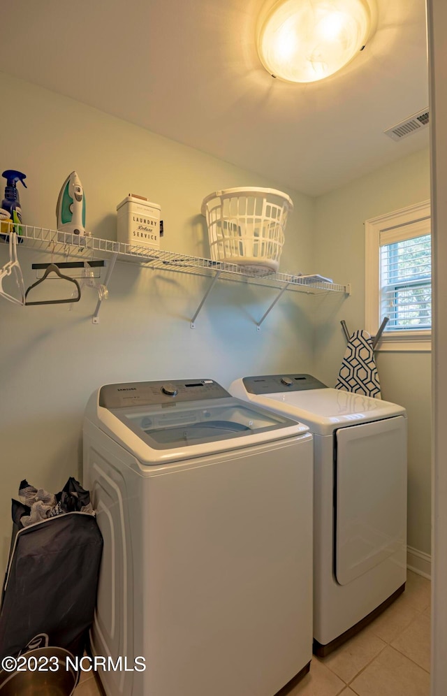 laundry room with independent washer and dryer and light tile patterned floors