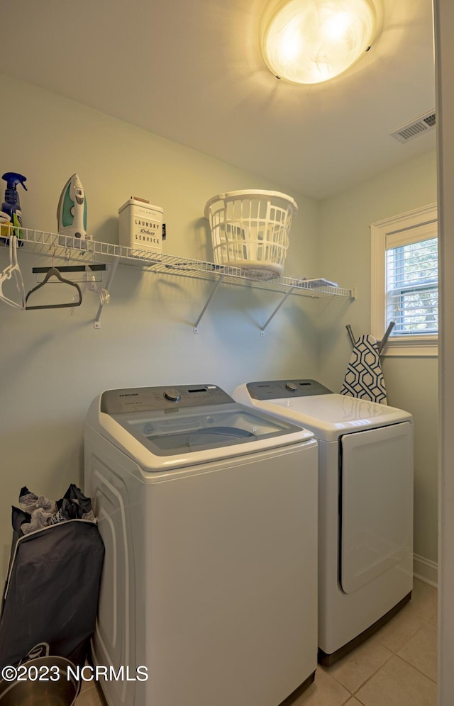 laundry room with independent washer and dryer and light tile patterned floors