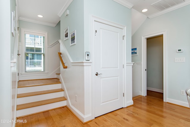 stairs with crown molding and light hardwood / wood-style flooring