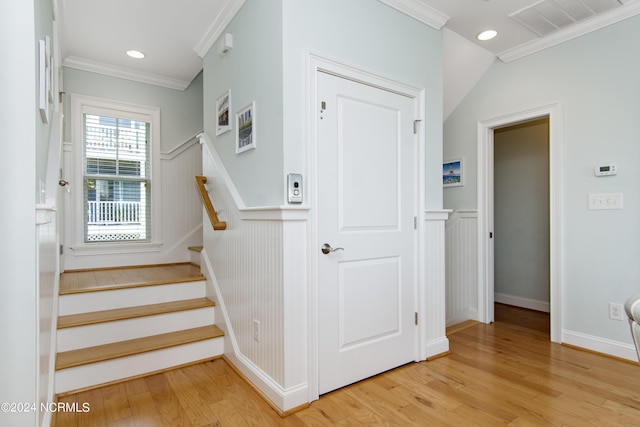 staircase with wood-type flooring and ornamental molding