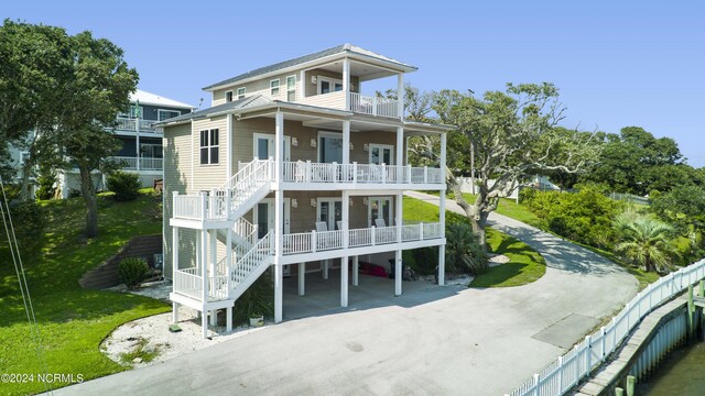 rear view of property with covered porch, a carport, and a balcony