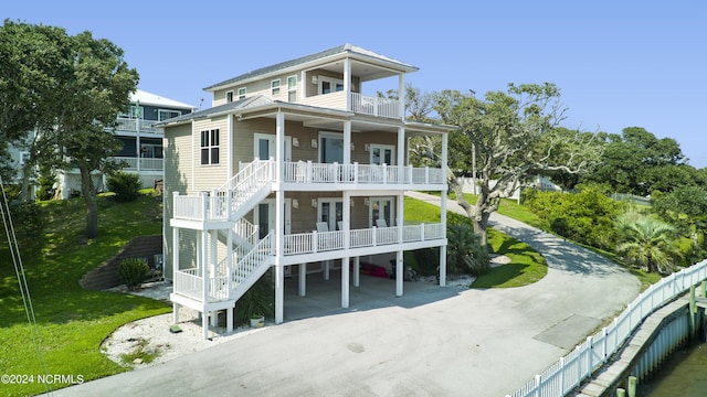 raised beach house featuring a carport, a balcony, and covered porch