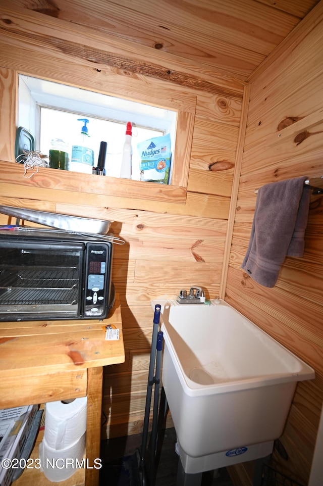 bathroom featuring wooden ceiling, sink, and wooden walls