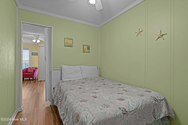 bedroom with ceiling fan, crown molding, and wood-type flooring