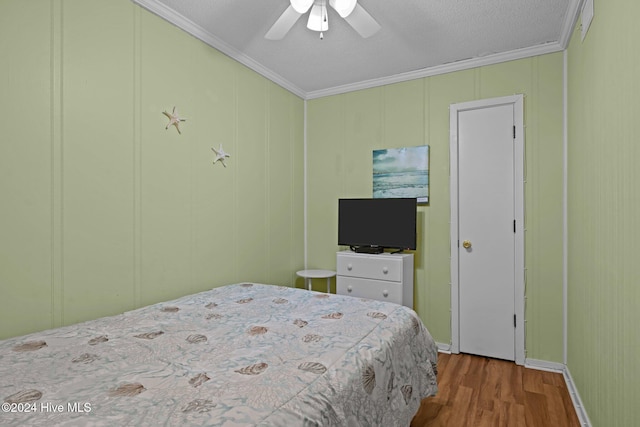 bedroom with wood-type flooring, ceiling fan, and crown molding