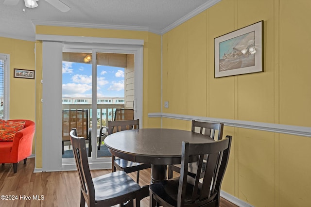 dining area featuring ceiling fan, ornamental molding, a textured ceiling, and light wood-type flooring