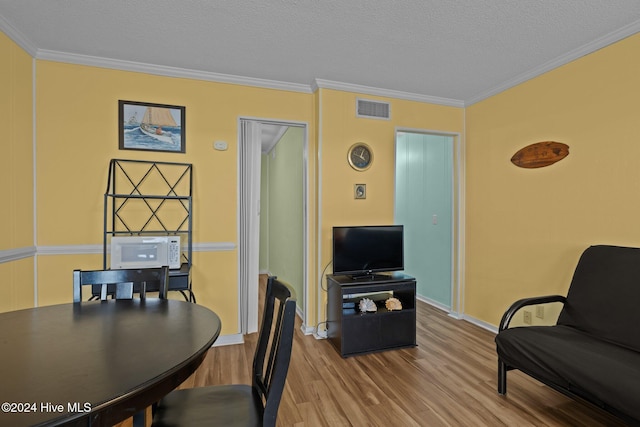 dining area featuring crown molding, light hardwood / wood-style flooring, and a textured ceiling