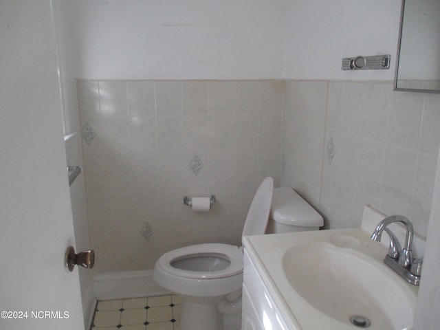 bathroom with vanity, tile walls, and toilet