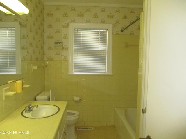 bathroom with vanity, toilet, tile walls, and a tub