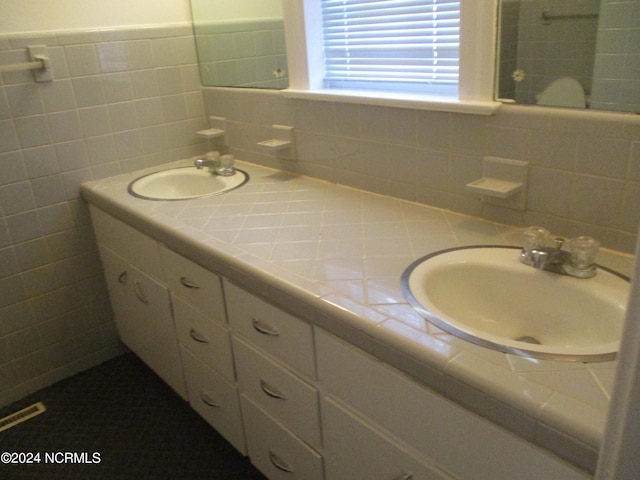 bathroom featuring vanity and tile walls