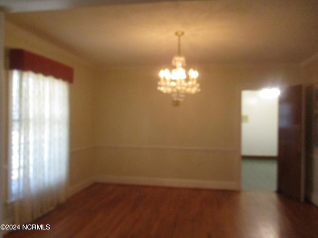 unfurnished room with wood-type flooring and a notable chandelier