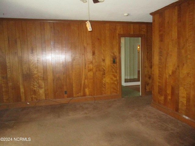 carpeted empty room featuring wooden walls