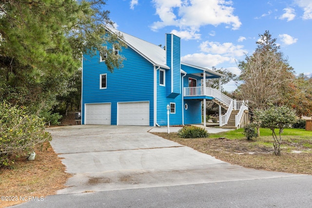 view of front of property featuring an attached garage, covered porch, stairs, concrete driveway, and a chimney