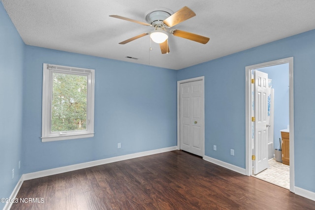 unfurnished bedroom featuring a textured ceiling, ensuite bathroom, ceiling fan, and dark wood-type flooring