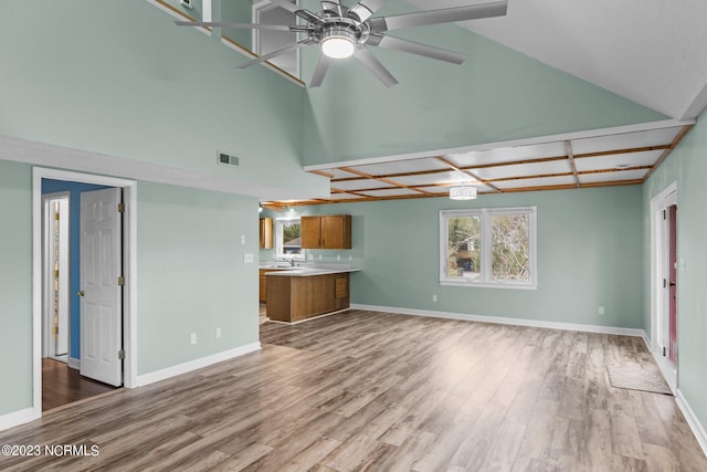 unfurnished living room with wood-type flooring, ceiling fan, and sink