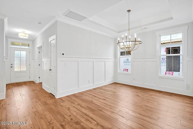 unfurnished dining area featuring a tray ceiling, light hardwood / wood-style flooring, and a wealth of natural light