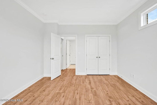 unfurnished bedroom with crown molding, light wood-type flooring, and a closet