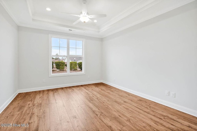 spare room with ceiling fan, ornamental molding, a tray ceiling, and light hardwood / wood-style flooring