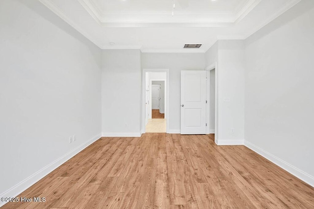 unfurnished bedroom featuring ornamental molding, a raised ceiling, and light hardwood / wood-style floors