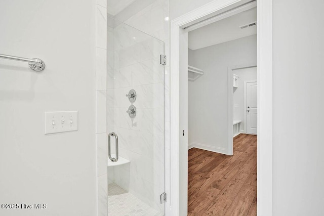 bathroom with hardwood / wood-style floors and a shower with shower door