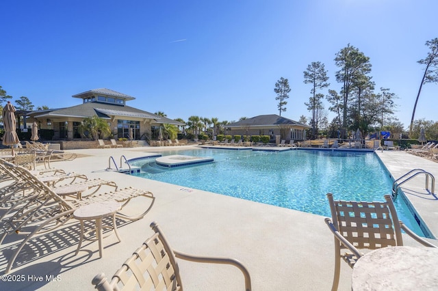 view of swimming pool featuring a hot tub and a patio area