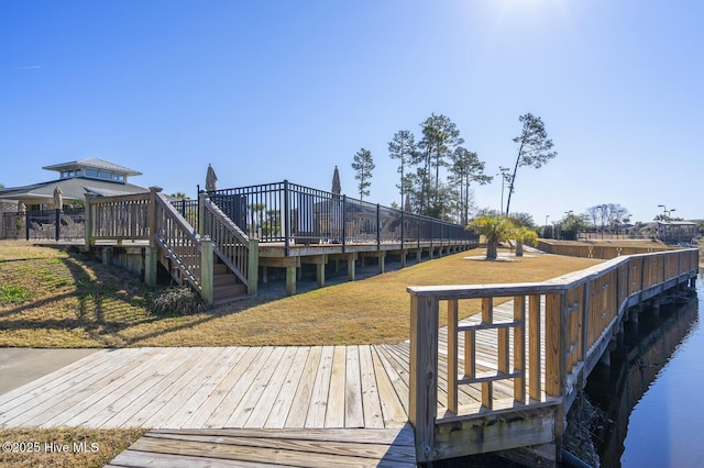 view of dock with a deck with water view and a yard