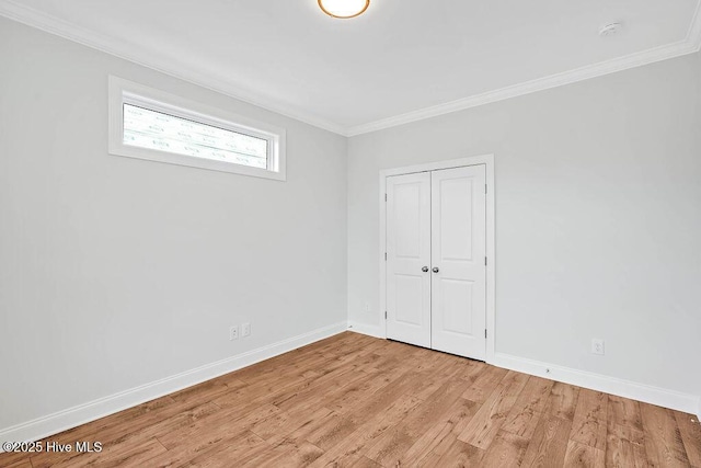 unfurnished bedroom with crown molding, light hardwood / wood-style floors, and a closet