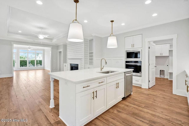 kitchen featuring appliances with stainless steel finishes, sink, white cabinets, hanging light fixtures, and a kitchen island with sink