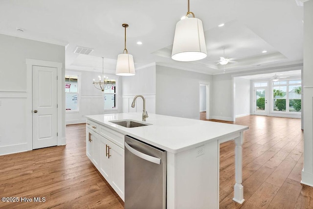 kitchen featuring sink, stainless steel dishwasher, a raised ceiling, an island with sink, and pendant lighting