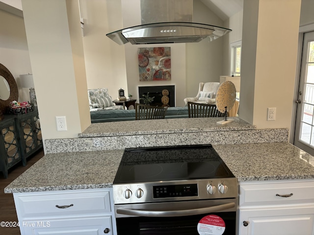 kitchen with stainless steel range, white cabinets, light stone countertops, and range hood