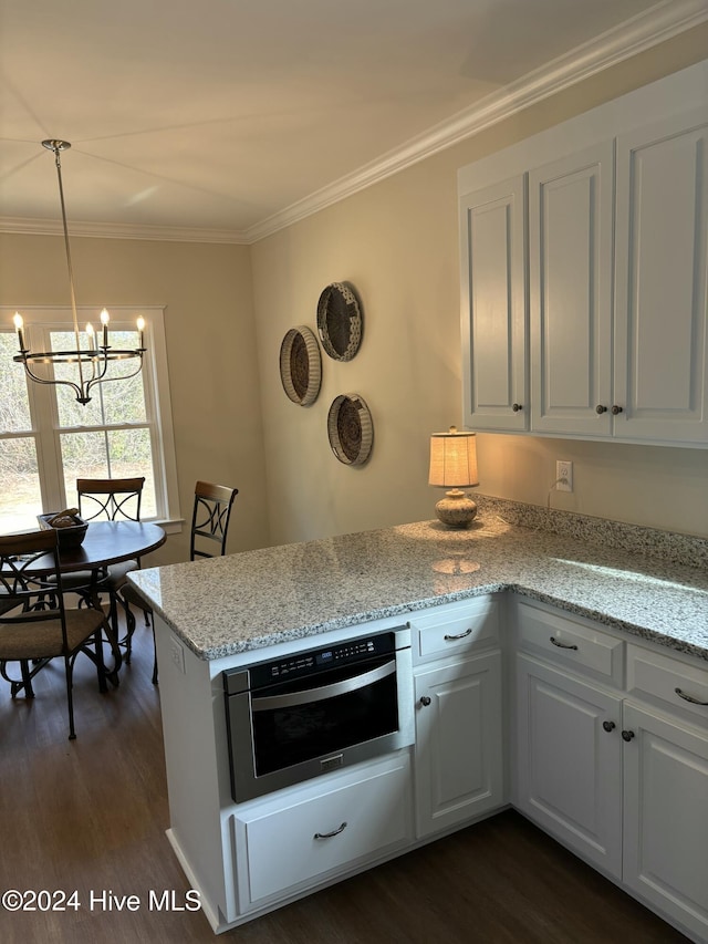 kitchen with light stone countertops, stainless steel oven, pendant lighting, dark hardwood / wood-style floors, and white cabinetry