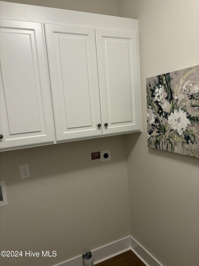 clothes washing area featuring electric dryer hookup and cabinets