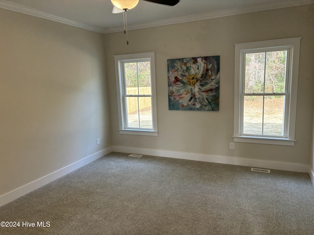 carpeted empty room featuring ornamental molding, ceiling fan, and a healthy amount of sunlight