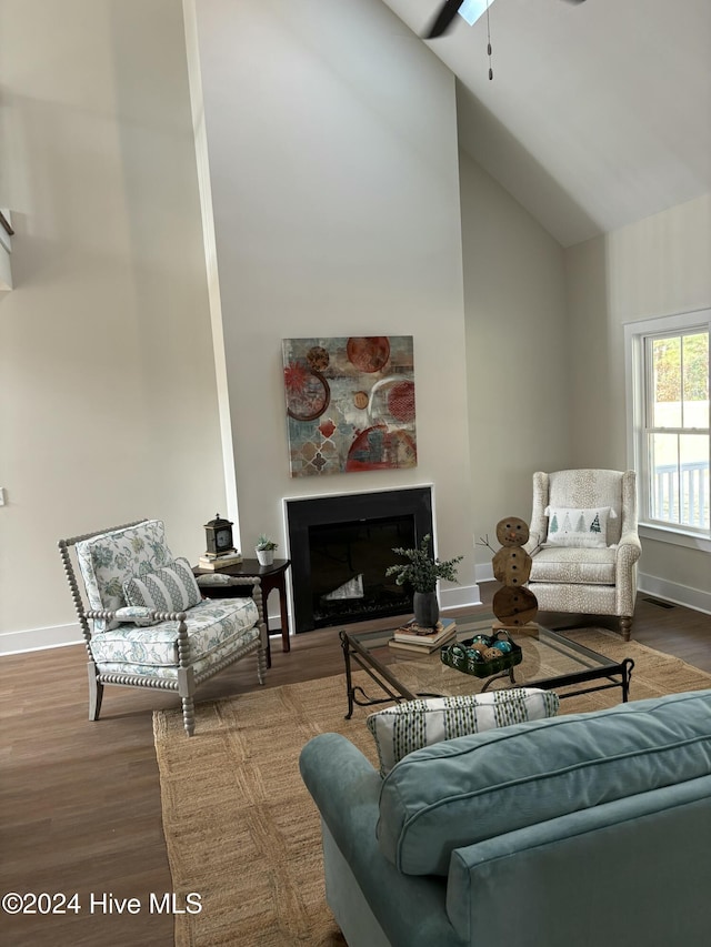 living room with hardwood / wood-style flooring, ceiling fan, and high vaulted ceiling