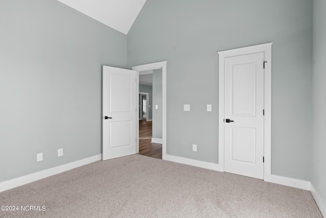 unfurnished bedroom featuring high vaulted ceiling and dark wood-type flooring