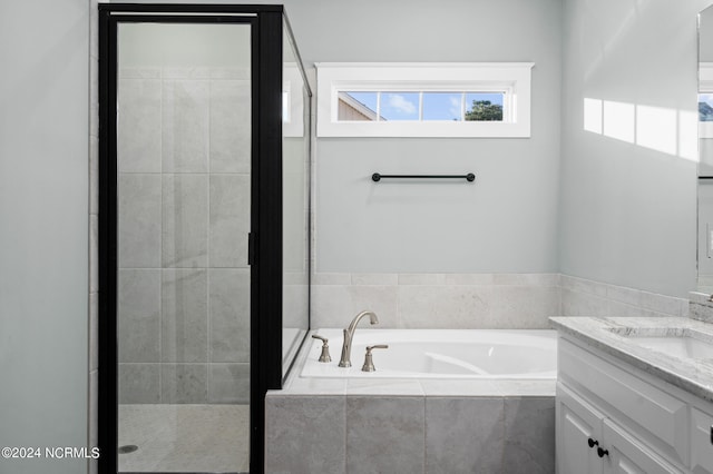 bathroom with shower with separate bathtub and vanity with extensive cabinet space