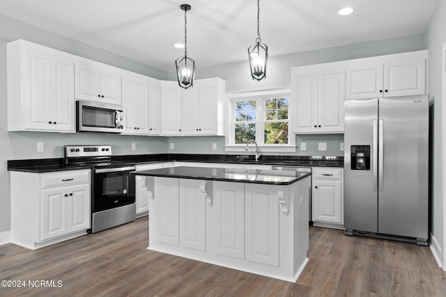 kitchen featuring appliances with stainless steel finishes, pendant lighting, a center island, dark hardwood / wood-style flooring, and white cabinetry