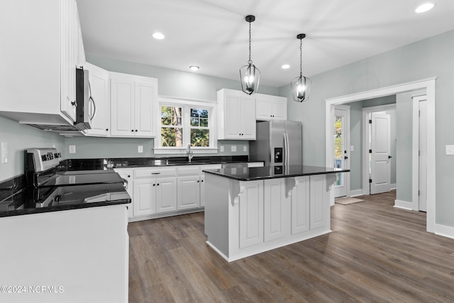 kitchen featuring appliances with stainless steel finishes, hanging light fixtures, a breakfast bar, dark hardwood / wood-style flooring, and white cabinets