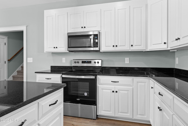 kitchen featuring white cabinets, dark stone counters, appliances with stainless steel finishes, and hardwood / wood-style flooring